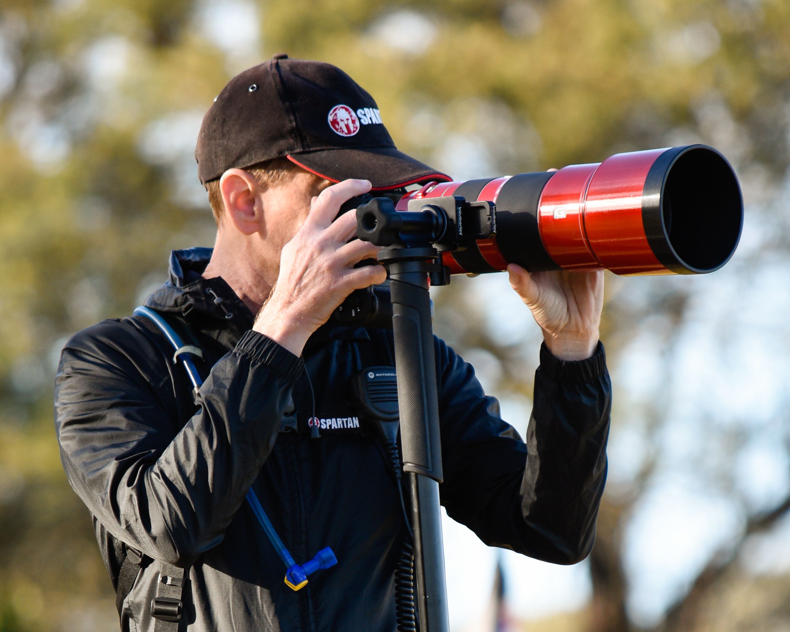 A sports photographer using a long red telephoto lens